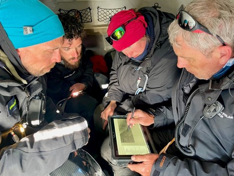 Four people plan a route using a toughbook