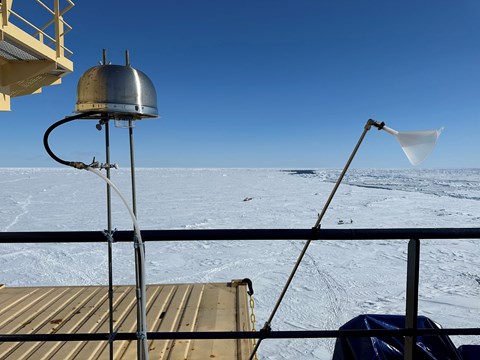 Instrument i plast och metall liknande en upp- och nervänd skål och en vit tratt invid relingen. I bakgrunden syns is och klarblå himmel. 