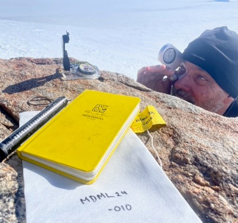 A man points an instrument at the horizon.