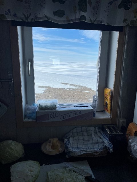 Genom en fönster syns milsvida glaciärer och blå himmel. 