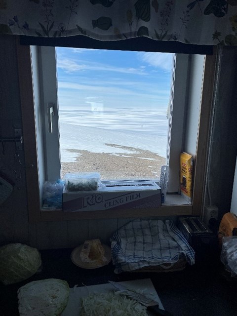 Genom en fönster syns milsvida glaciärer och blå himmel.