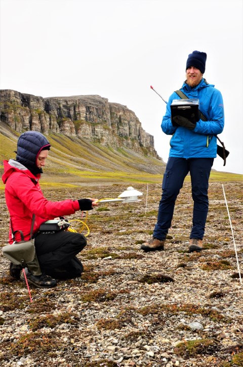 Maja Sundqvist mäter albedo, det vill säga hur mycket av det inkommande ljuset som reflekteras, i ett kontrollområde. Tobias Grassauer håller protokoll. Nära Ny-Ålesund på Svalbard.