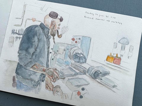 Peson i blå kläder står vid en svarv