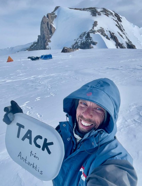 En man håller upp en skylt med texten Tack till Antarktis.