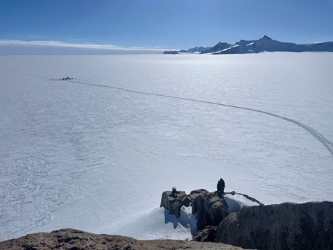 Vita vidder med några bergstoppar till höger i bild. På isen syns små prickar där fältlägret är uppställt. 