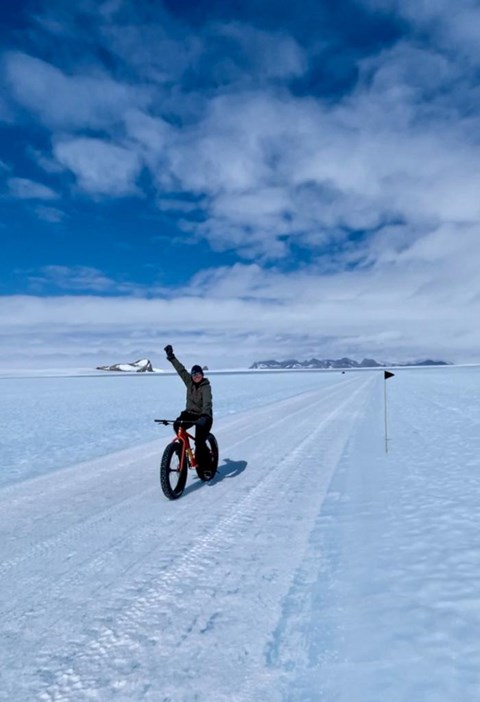 Person på en fat bike som ler och sträcker upp sin hand i luften. 