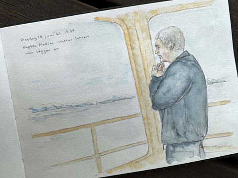 Person i blå kläder håller ena handen under hakan och tittar ut över vattnet