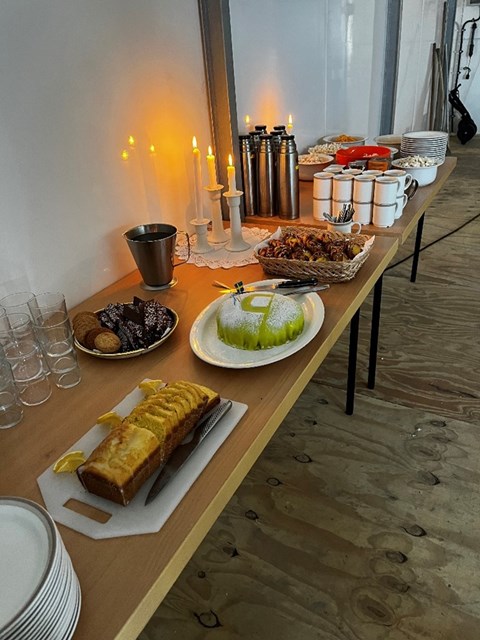 A coffee table is set up with cakes, buns and popcorn.