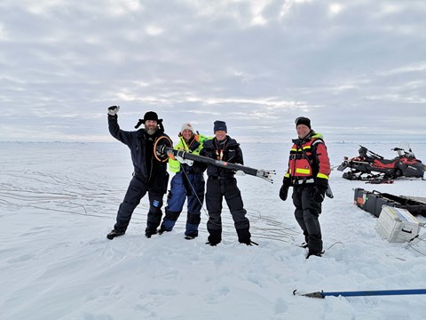 Fyra personer på isen som håller i ett instrument