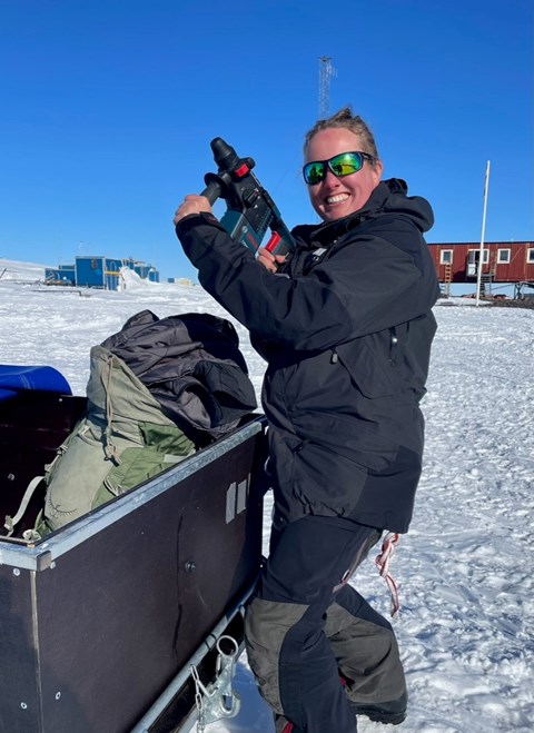 Jane Lund Andersen, Postdoc at Stockholm University, pulls the percussive drill out of the sled. In the background Wasa and some housing modules.
