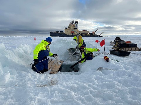 Forskare arbetar på isen med Oden i bakgrunden