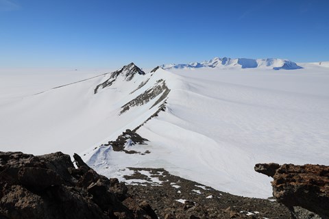Antarctic mountain peaks rise out of the ice and snow cover.