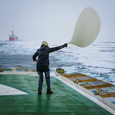 Doktorand som jobbar hårt för att hålla ordning på en radiosondballong på Odens helikopterdäck under en storm i Norra ishavet.