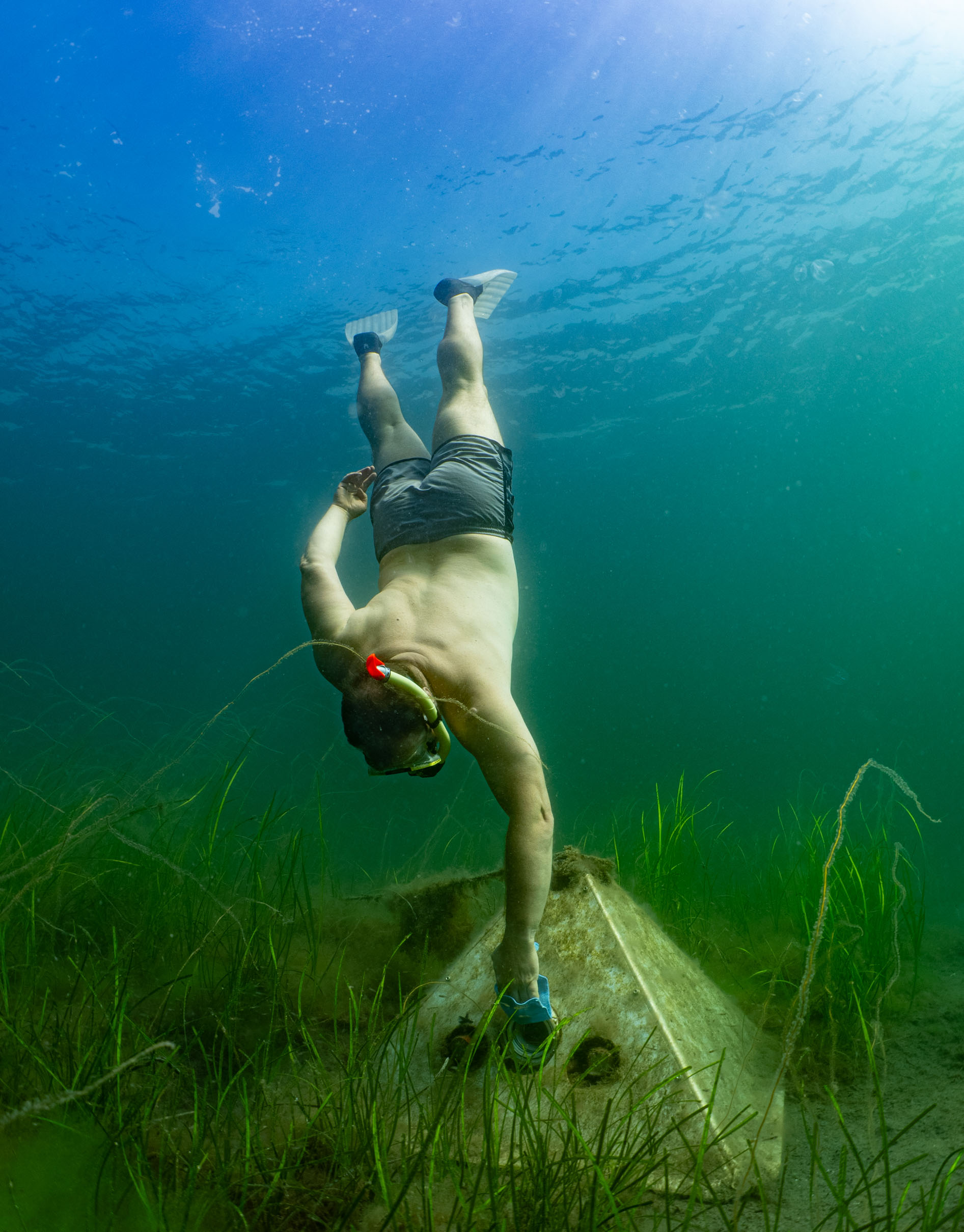 Person som snorklar och dyker ner och putsar undervattenskameran.