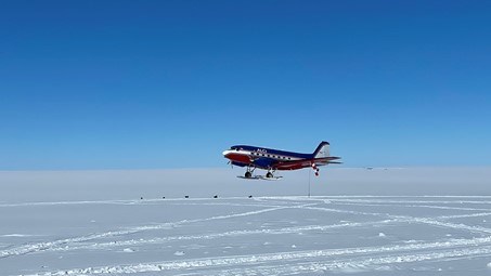 Ett blått, vitt och rött flygplan landar på isen.