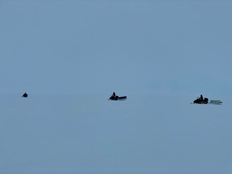 Three snowmobile drivers out on the ice.